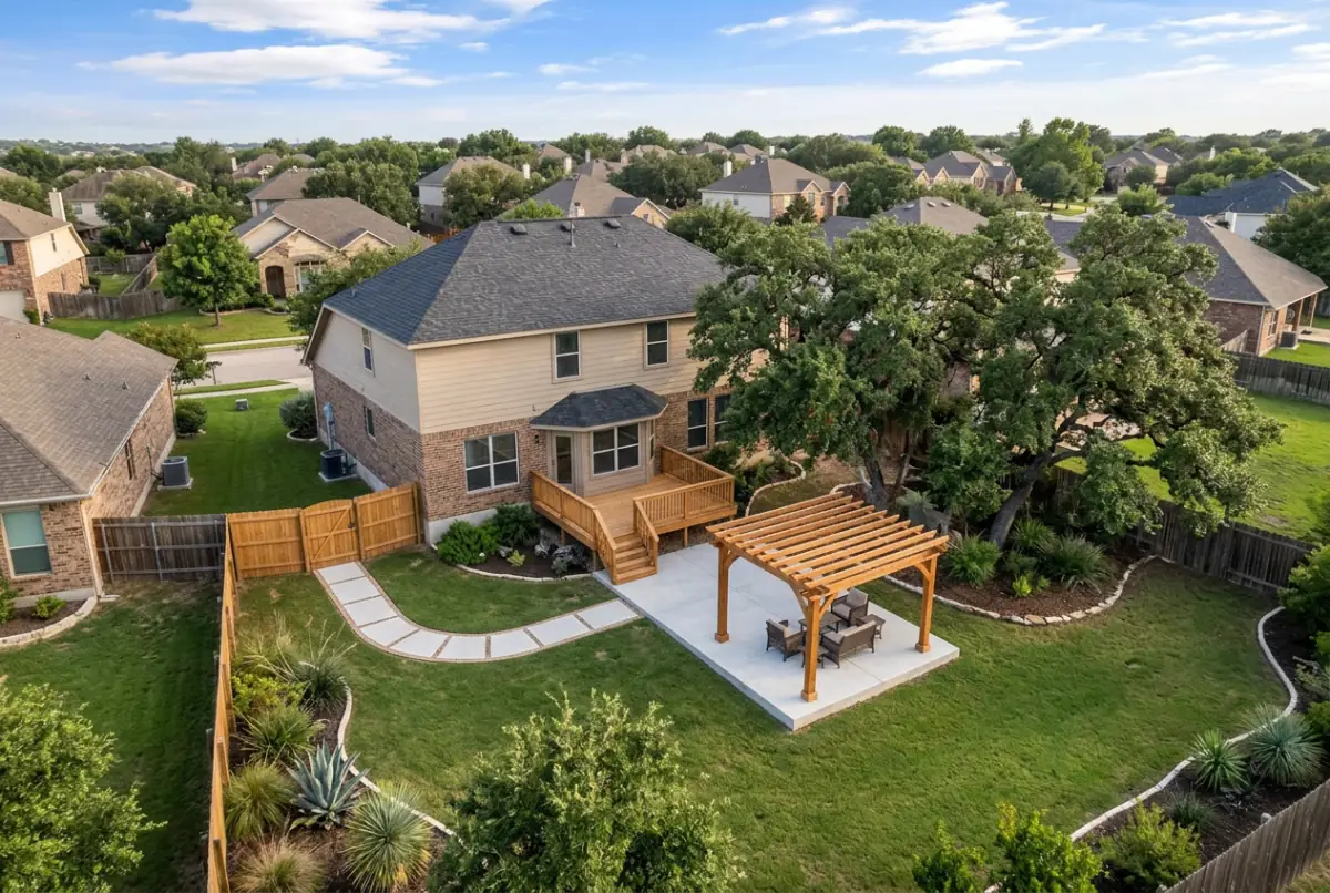 Fenced subdivision backyard with a wood deck at the back door and a cedar pergola on the lawn